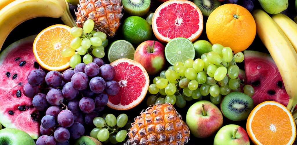 Heaped seasonal fruits including grapes, citrus fruit and watermelon